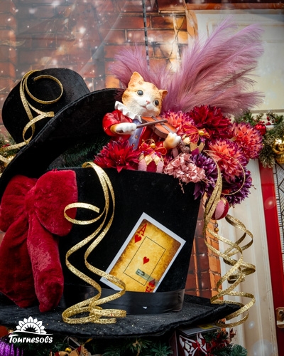 Chat en costume Renaissance jouant du violon sur un chapeau décoratif.